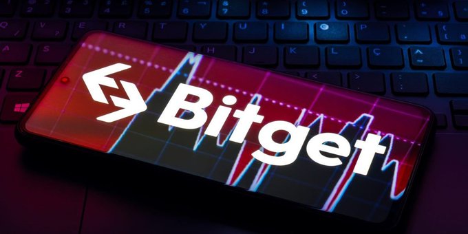 A smartphone displaying the Bitget logo and a fluctuating stock chart rests on a laptop keyboard, visually representing the crypto exchange's market movements as it prepares to withdraw from the Japanese market starting November 1 due to regulatory requirements.