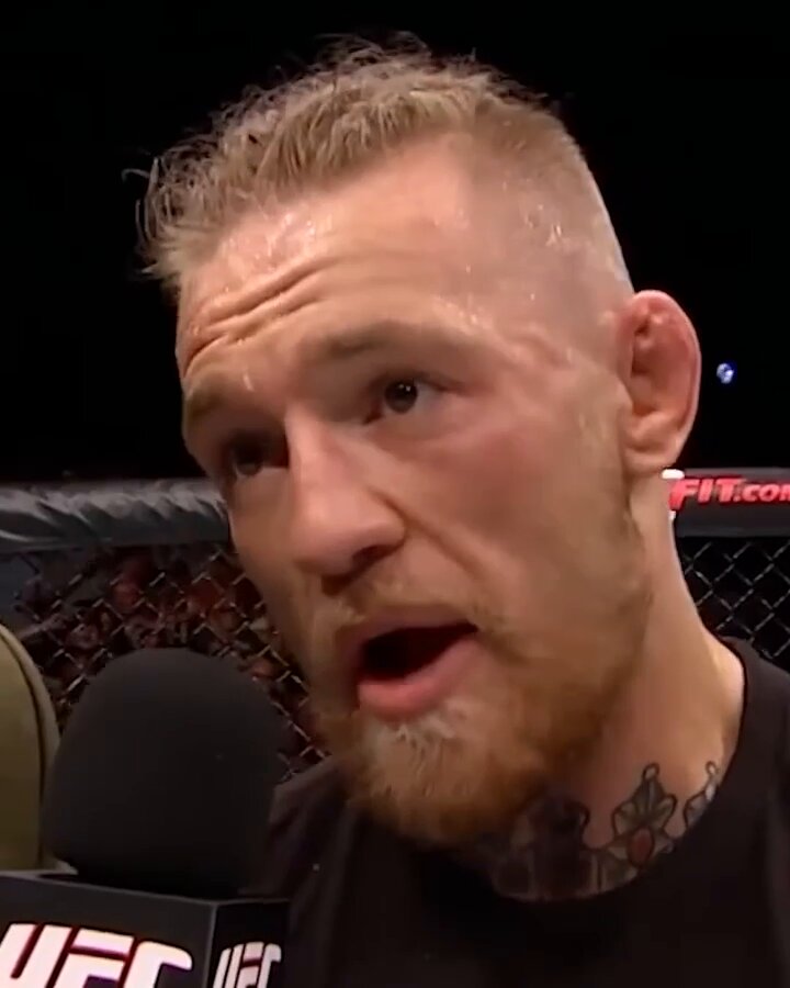 The image features a man with a shaved head wearing a black shirt, standing behind a microphone. He appears to be talking or giving a speech, possibly at an event like UFC. The background of the image shows a cage, which could indicate that this is taking place in a boxing match or similar sporting event. The caption "Perps on Polymarket" suggests that there might be some controversy or conflict surrounding the event depicted in the image.