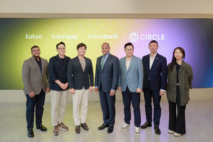 Seven business professionals pose in front of a colorful backdrop displaying the logos of "kakao," "kakaopay," "kakaobank," and "CIRCLE," representing the signing of an MOU between Circle and Kakao Group to explore blockchain-based payment infrastructure and USDC integration in Korea.
