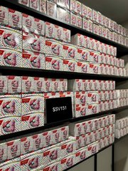 Rows of sealed Pokémon Scarlet & Violet 151 booster boxes are stacked on warehouse shelves, with an Offerbook displaying "$SV151" posted among the inventory. The image visually reinforces the post by showing the physical sealed product reserves backing the $SV151 on-chain loan offers.