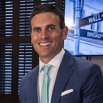 A smiling man in a blue suit with a mint tie poses in front of a screen displaying "WALL STREET BROAD" and a "THE BLOCK" logo, aligning with a post about Chainlink's role in blockchain, AI, stablecoins, and robotics.