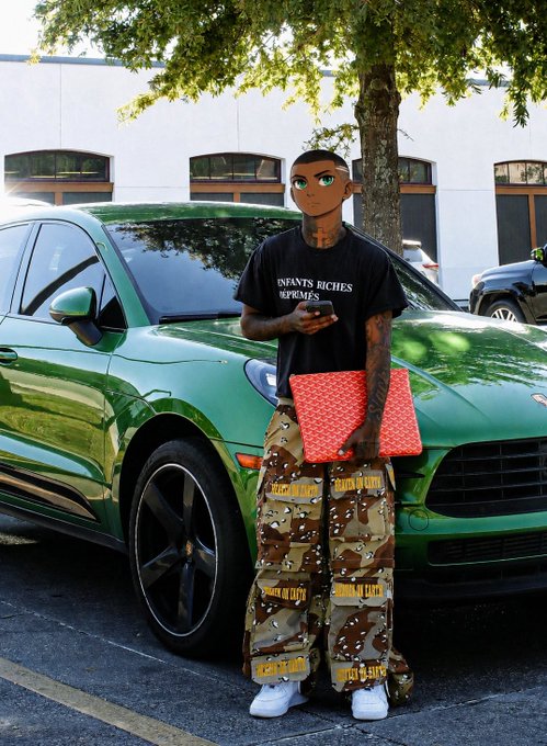 A person with a digitally altered cartoon face, wearing a black 'INFANTS RICHES' t-shirt, camouflage pants, and holding a red patterned bag, stands beside a green Porsche.