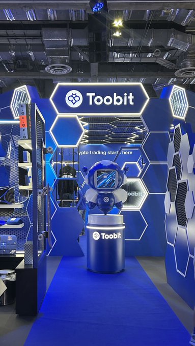 A trade show booth for 'Toobit' cryptocurrency exchange featuring a blue and white astronaut figure and the tagline 'crypto trading starts here'.