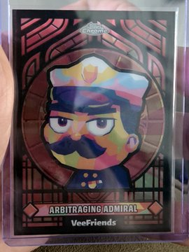 A holographic trading card titled 'ARBITRAGING ADMIRAL' from the VeeFriends collection, featuring an illustrated naval officer character with a mustache and captain's hat.