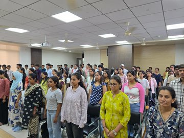 Group of young women standing indoors, possibly during a class or assembly, with one woman in a yellow patterned shirt in the foreground.