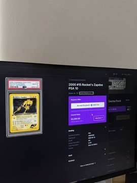 A computer monitor displaying a PlayStation account page for "2006 #P5 Rocker's Zeppelin PSA 10," with a Pokémon card in a protective case taped to the monitor.