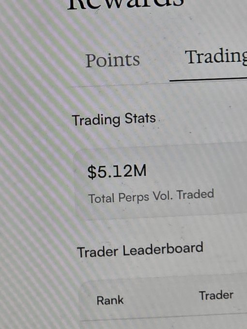 A close-up photo of a screen showing a "Rewards" dashboard with "Trading Stats" displaying "$5.12M Total Perps Vol. Traded" and a "Trader Leaderboard" section below.