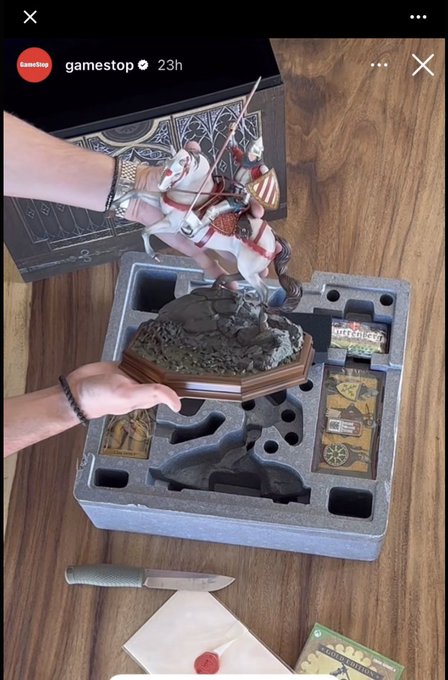 The image shows a GameStop Instagram story featuring a detailed warrior figurine being placed into its protective foam packaging, with accessories like a knife and cards visible around it.

The image relates to the post through the metaphor of "choices" and decision-making—the figurine being carefully placed into its custom-cut foam case symbolizes how a person's choices and life events fit together to shape their identity, much like how each component is carefully designed to complete the whole.
