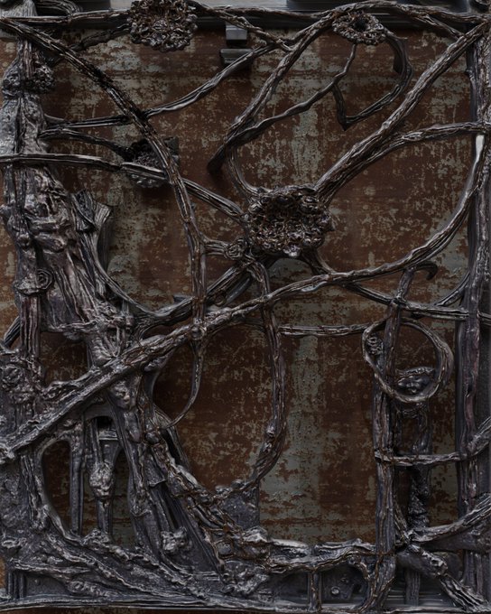 A close-up of an ornate dark metal decorative panel featuring intricate intertwining branches and floral motifs against a weathered reddish-brown background.