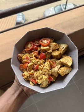 A hand holds a plate of scrambled eggs with cherry tomatoes and roasted potatoes, reflecting the post's preference ranking of chicken over potatoes over oats, with the potatoes visible in the meal.