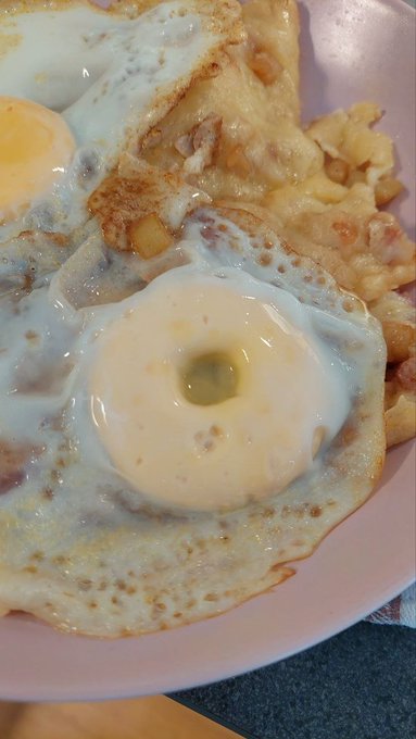 A plate of sunny-side up eggs served over golden hash browns with crispy browned edges. The post draws a parallel between "bleeding" yolks and the bleeding market charts, suggesting the eggs and home-cooked foundation represent the "real community" building solid ground amid market chaos.