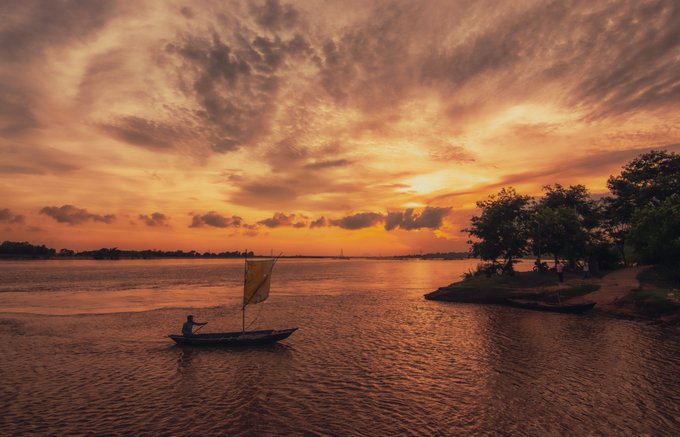 The image features a man sailing a boat across a body of water, with an orange sail billowing in the wind. The sky above them is painted in shades of orange, creating a beautiful backdrop for their journey. In the background, there are trees that add depth and texture to the scene. The post also includes text that reads "Collected by @growthrev & @Shamspranto1 Thank you so much !!! Nineteen - Twenty" which suggests that this image was taken during the Teen years of someone's life.