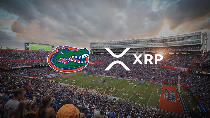 A crowded Florida Gators football stadium is shown at sunset with the iconic Gator head logo alongside the Ripple "X" logo and "XRP" text overlaid in the center, visually representing the newly announced multi-year partnership between Florida Athletics and Ripple to integrate XRP cryptocurrency into Gator Nation starting with the 2026 football season.