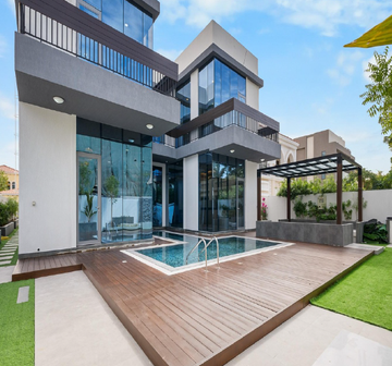 A modern two-story house featuring large glass windows, a wooden deck, and a small swimming pool in the foreground.