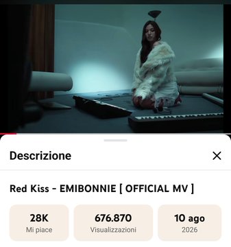 The image shows a YouTube video page for "Red Kiss - EMIBONNIE [ OFFICIAL MV ]" with 676,870 views, uploaded 10 months ago in 2026, featuring a moody scene of a woman in white fur kneeling by a piano. The screenshot perfectly captures the moment of anticipation described in the post, which celebrates Red Kiss nearing the 700k views milestone and sets goals for other EmiBonnie music videos.
