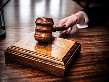 A wooden gavel rests on a matching sound block, with a hand reaching toward it, symbolizing the judge's ruling. The image reflects the post about the film director receiving a 30-month prison sentence for misusing $11 million of Netflix's production funds on gambling.