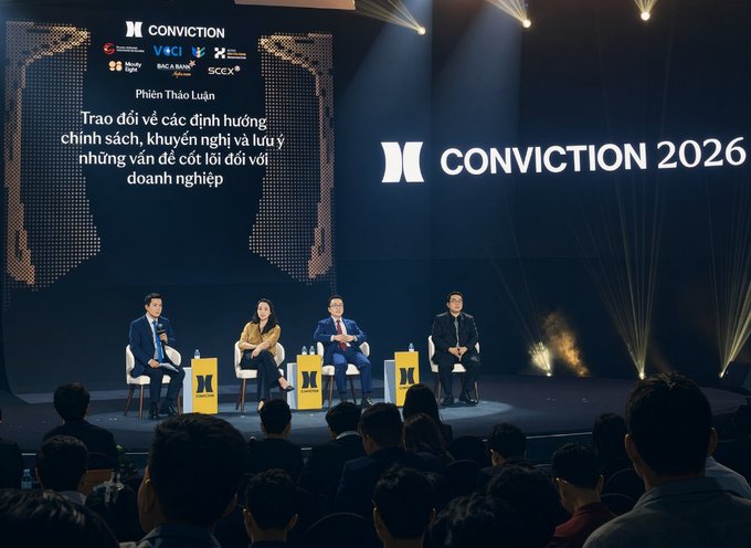 A panel discussion at the 'CONVICTION 2026' conference, with four speakers seated on stage and Vietnamese text about policy challenges for businesses displayed on screen.
