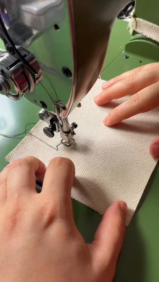 The image shows a person's hands operating a sewing machine with a green background. The focus of the image is on the hands holding the fabric under the needle, indicating that they are engaged in sewing or crafting. The photo appears to be from a documentary about the birth of the SewEx brand, as suggested by the caption "A documentary about the birth of the piece SewEx."