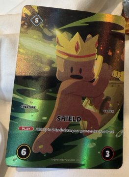 A holographic trading card displays a Shield Goomba character from Super Mario with the text 'SHIELD', 'PLAY', and stats of 5, 6, and 3.