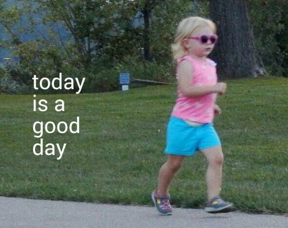 A young blonde girl in a pink top and blue shorts runs along a path wearing sunglasses, with the text 'today is a good day' overlaid.