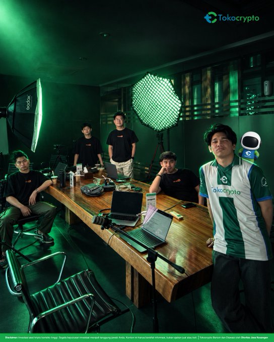 A team of six people pose around a wooden conference table in a green-lit podcast studio, with two large octagonal softbox lights visible and several laptops open on the table. The Tokocrypto logo appears in the top right corner and on a jersey worn by one team member, while the watermark in the lower left credits photographer Disuntuk Investor dan Krypto terlebih tinggi and illustrator Aledsa Java Kuswanto.

The image supports the post by showing the Tokocrypto team in what appears to be a podcast recording setup, visually teasing the upcoming program announcement.