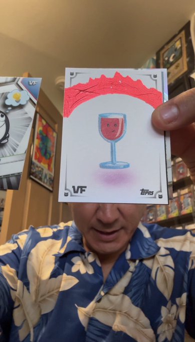 A person wearing a floral shirt holds up a 1/1 Topps Chrome Sketch "Last Glass Standing" VeeFriends card featuring a smiling wine glass illustration, with "VF" and "Topps" logos visible at the bottom, celebrating their rare pull from a personal blaster box.