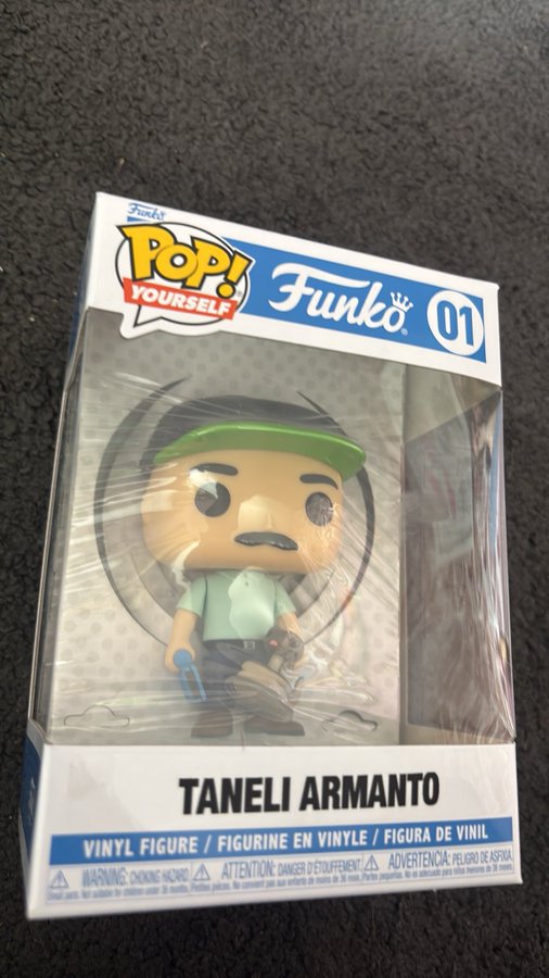 A Funko 'POP! YOURSELF' vinyl figure box #01 sits on a dark surface, labeled 'TANELI ARMANTO' with a character wearing a green cap and shirt.