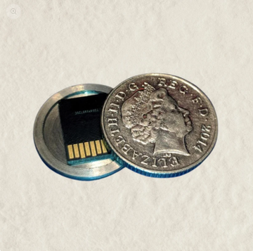 A tiny SD card sits next to a British 50 pence coin for scale, with the post explaining that an ArcaSafe device protects these easily-misplaced microSD cards.