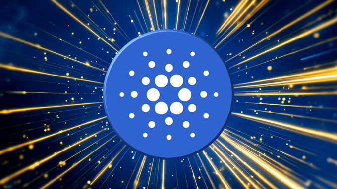 The blue Cardano logo centered on a background of radiating golden light streaks against a dark blue backdrop.