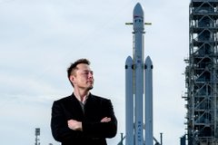 A confident man in a suit stands with arms crossed in front of a massive SpaceX rocket on its launch pad, visually evoking the company's ambitious, forward-looking image—a stark contrast to the post's bearish warning that ticker $SPCX will crash to $80 after an Aug 6 lock-up expiration unlocks 911M shares.