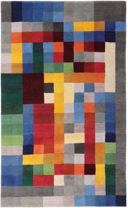 A colorful geometric area rug featuring a pixelated, Bauhaus-inspired pattern with rectangular blocks of red, blue, yellow, green, gray, and other hues.