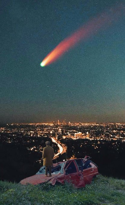 A person stands atop a rusted red car on a grassy hill overlooking a sprawling cityscape at night, gazing up at a brilliant green-tinged comet with a fiery orange tail streaking across the starry sky. The cinematic scene, captioned "Gm fren," evokes a surreal, dreamlike moment of quiet wonder between friends beneath a spectacular celestial event.