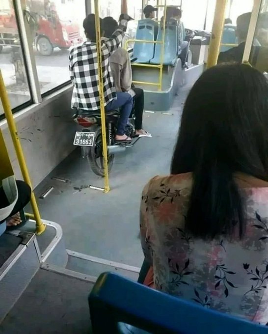 A candid shot inside a bus shows a passenger with a motorcycle parked next to them on the vehicle, with license plate '81663'.
