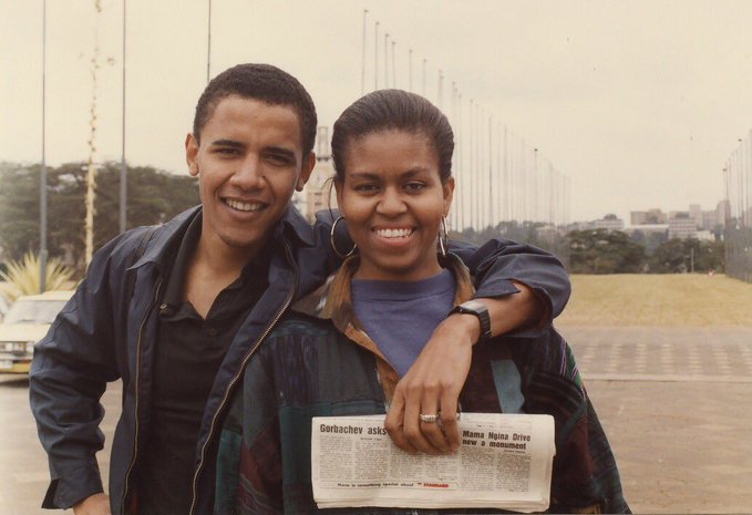 A vintage photograph of a smiling young couple posing together, with the woman holding a newspaper displaying the headline 'Gorbachev asks...Nana Nzima Drive now a monument'.