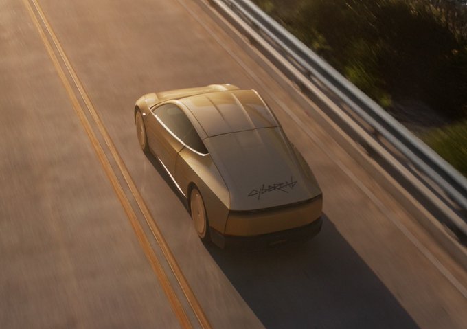 A sleek golden Tesla Cybercab cruises down a sunlit road with graffiti-style "CYBER" markings on its rear, embodying the post's sentiment as a moving work of art.