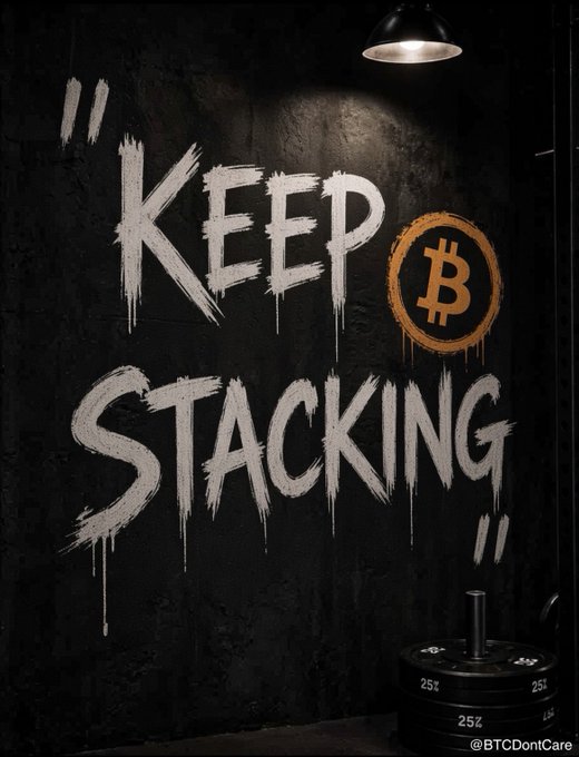 Graffiti-style white text reading 'KEEP STACKING' alongside a Bitcoin symbol is painted on a dark wall above weight plates, tagged '@BTCDontCare'.