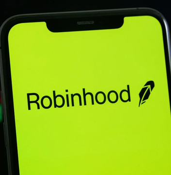 The image displays the Robinhood logo in black text on a vibrant green background, shown on a smartphone screen with the company's distinctive feathered icon beside the name. This visual ties directly to the news that Robinhood is expanding its zero-fee Bitcoin and crypto trading services to U.K. customers through its Bitstamp integration.