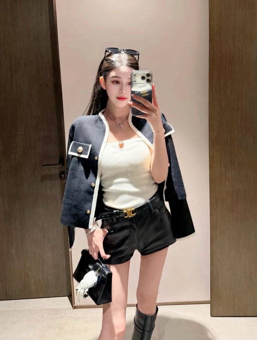 A stylish woman captures a mirror selfie, wearing a navy jacket over a white top and black shorts, reflecting a theme of self-examination echoed in the quote, "Using a person as a mirror allows one to understand gains and losses."