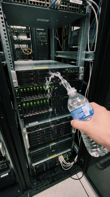 A hand pours water from a plastic bottle onto a rack of stacked server equipment in a data center, with water visibly splashing across the servers. The image humorously depicts the post's "pour out water on Base Chain" challenge, suggesting someone is literally dousing blockchain infrastructure with water.