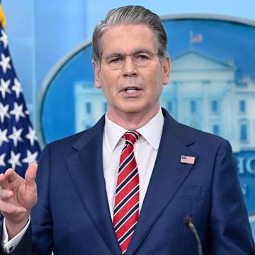 Treasury Secretary Scott Bessent speaks at a podium in front of a White House backdrop, gesturing while addressing reporters. The image accompanies news that the US may seize $1 billion in Iran-linked crypto this week.
