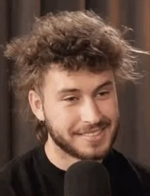 A young man with curly brown hair and a beard smiles broadly while sitting in front of a microphone, likely during a podcast recording. The image appears to show "Threadguy," the crypto personality referenced in the headline about closing his Zcash position for a $315,000 profit.