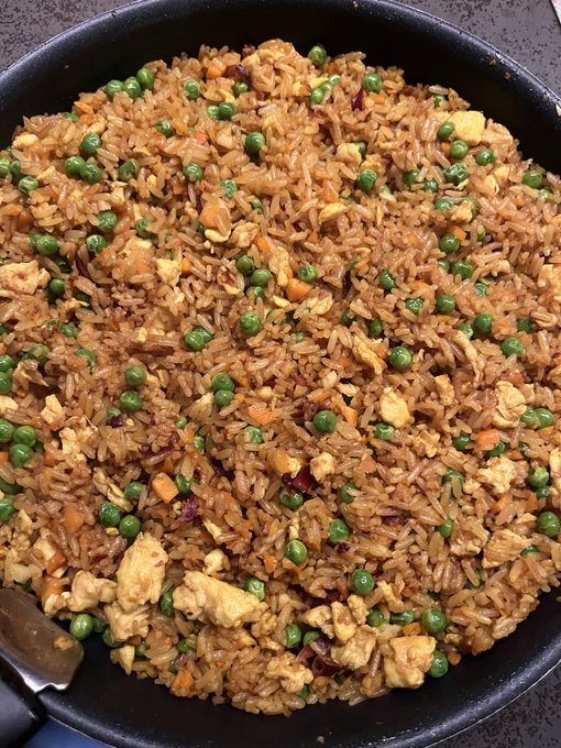 A pan filled with homemade fried rice featuring bacon, scrambled eggs, peas, carrots, and garlic, matching the post's description of a successful one-pan meal cooked with simple ingredients.