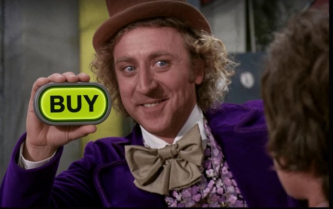 Gene Wilder as Willy Wonka in a purple coat and top hat, smiling while holding up a large green "BUY" button.