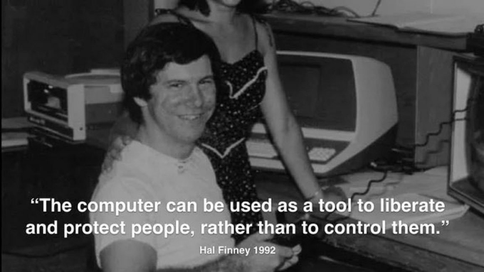 A black-and-white photo shows a smiling man seated at a desk with vintage computer equipment, while a woman in a polka-dot dress stands behind him; overlaid text reads "The computer can be used as a tool to liberate and protect people, rather than to control them." — Hal Finney 1992, paying tribute to the late cypherpunk and early Bitcoin contributor.