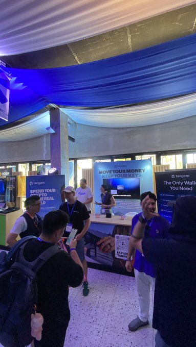 People gather at a Tangem crypto booth at an event, with promotional banners reading 'MOVE YOUR MONEY, KEEP YOUR KEYS' and 'The Only Wallet You Need' visible.
