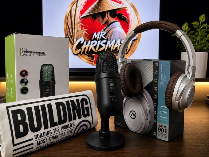 A streaming setup featuring an RGB Professional Live Microphone, CLM 901 headphones, a 'BUILDING' book, and a monitor displaying 'MR CHRISTMAS' artwork.