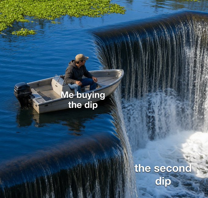 A man in a small boat sits near the edge of a waterfall, labeled "Me buying the dip" while the waterfall itself is labeled "the second dip," humorously illustrating the futility of trying to time the market as the boat teeters on the brink of another drop.