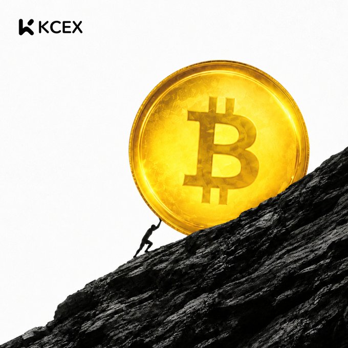 A KCEX promotional image featuring a tiny figure pushing a giant golden Bitcoin coin up a steep dark rocky hill.