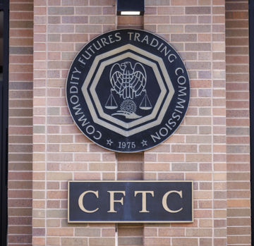 A circular emblem mounted on a brick wall displays the official seal of the "Commodity Futures Trading Commission" with "CFTC" and "1975" below, representing the regulatory body at the center of the dispute over perpetual futures classification mentioned in the post.