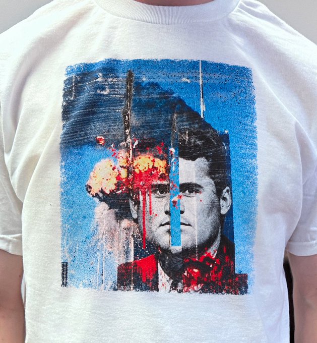 A white t-shirt featuring a graphic print of a black and white man's portrait overlaid with a colorful mushroom cloud explosion and red paint drip effects.